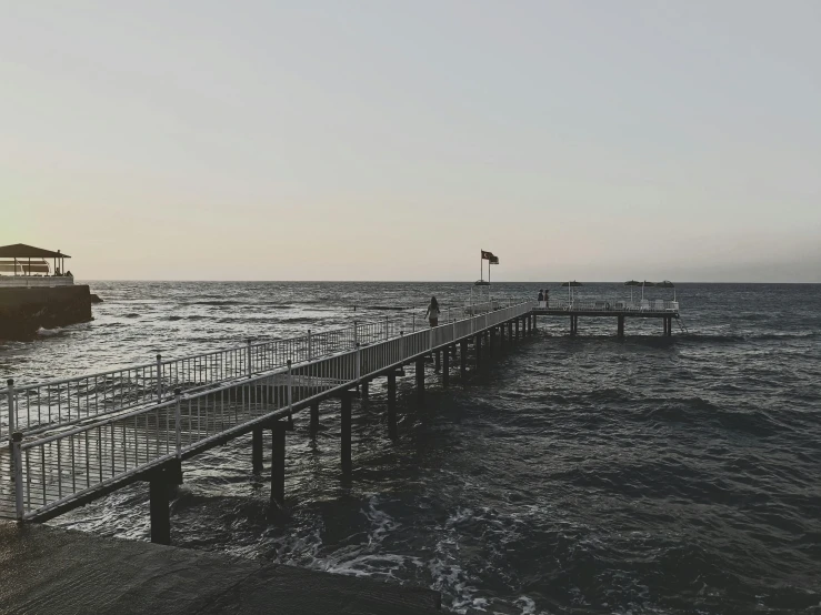 a boat sitting on top of a body of water next to a pier, by Tamas Galambos, pexels, romanticism, people walking into the horizon, slight haze, instagram photo, hd footage