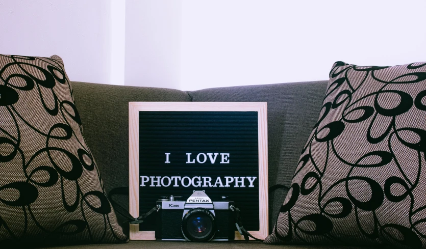 a book sitting on top of a couch next to a pillow, a polaroid photo, by Julia Pishtar, unsplash contest winner, portrait photo of a backdrop, camera low, advertisement photography, on a canva