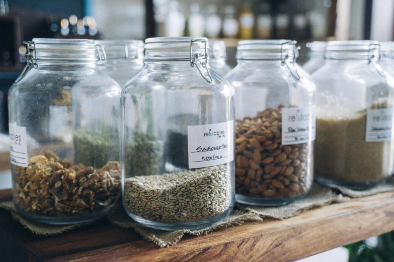 a row of glass jars filled with nuts and seeds, a photo, pexels, renaissance, small hipster coffee shop, herbs, magnesium, thumbnail