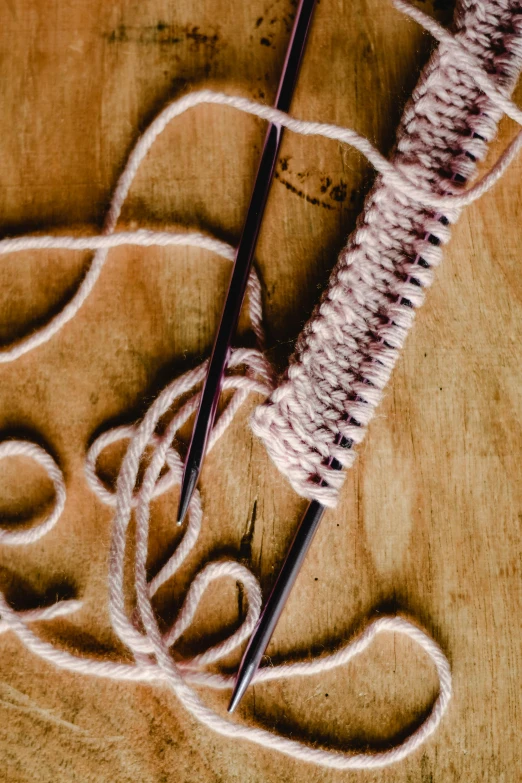 a pair of knitting needles sitting on top of a wooden table, unsplash, process art, brown and pink color scheme, seams stitched tightly, promo image, ignant