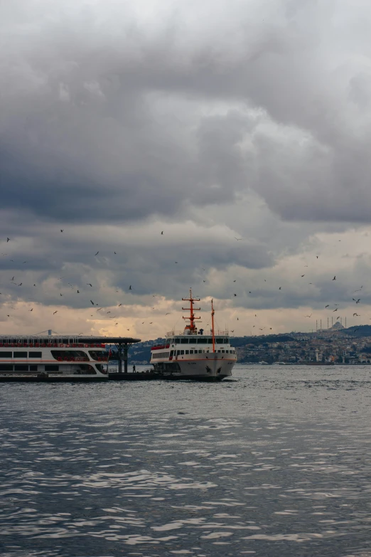 a large boat floating on top of a large body of water, a mosaic, inspired by Yasar Vurdem, flickr, overcast!!!, istanbul, random circular platforms, brooding clouds'