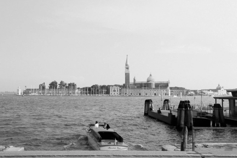 a black and white photo of a boat in the water, venice biennale, city in the distance, medium format, historical image