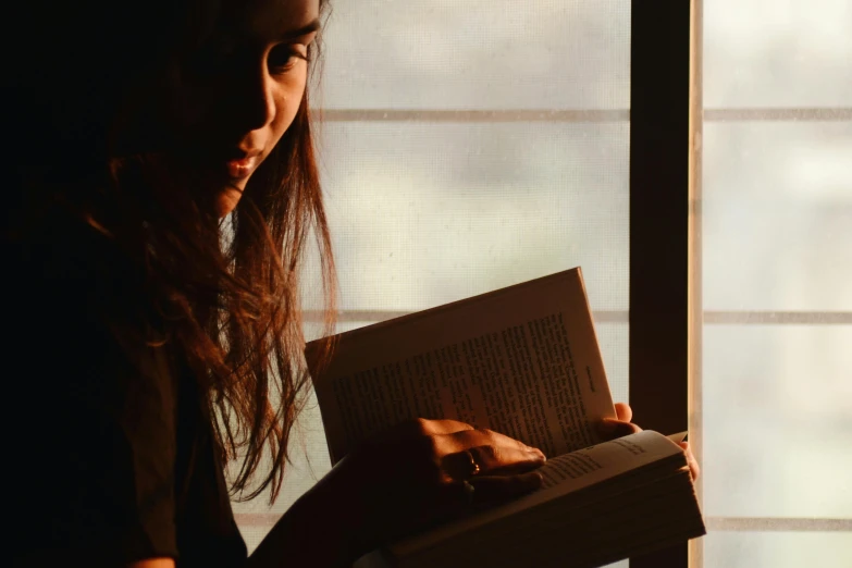 a woman reading a book in front of a window, pexels contest winner, glowy light, asian woman, uncropped, lit from the side