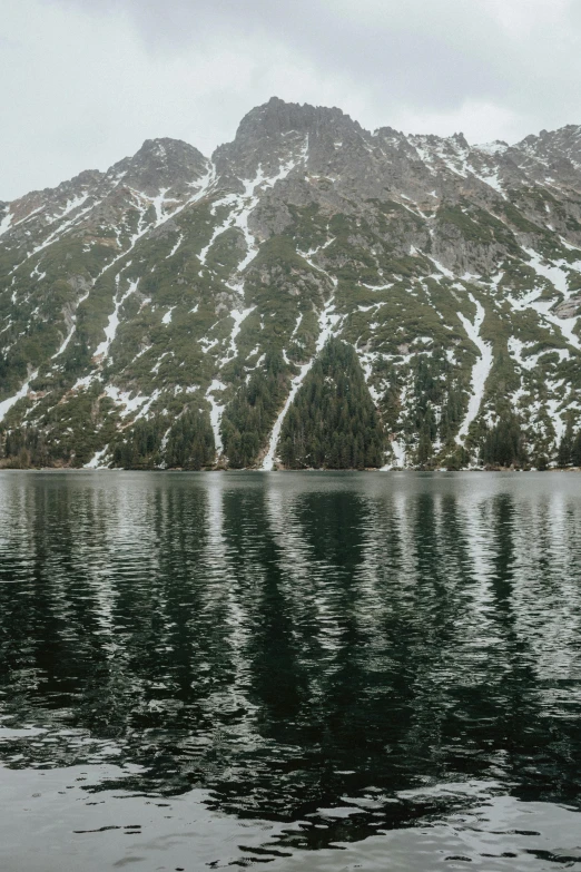 a body of water with a mountain in the background, ultrawide image, snowy mountain, dark green water, bad photo