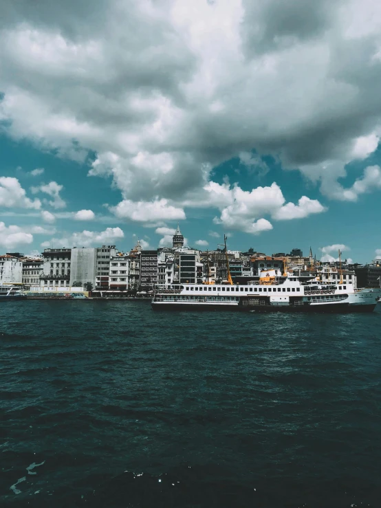 a group of boats floating on top of a body of water, a colorized photo, inspired by Elsa Bleda, pexels contest winner, hurufiyya, fallout style istanbul, 🚿🗝📝, grey cloudy skies, photo taken on fujifilm superia