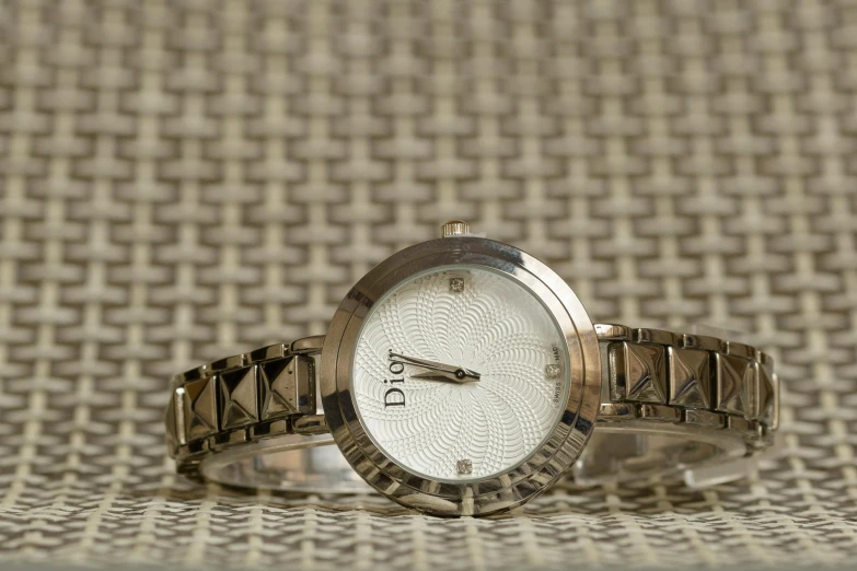 a close up of a wrist watch on a table, by David Simpson, christian dior style, thumbnail, white: 0.5, delicate patterned