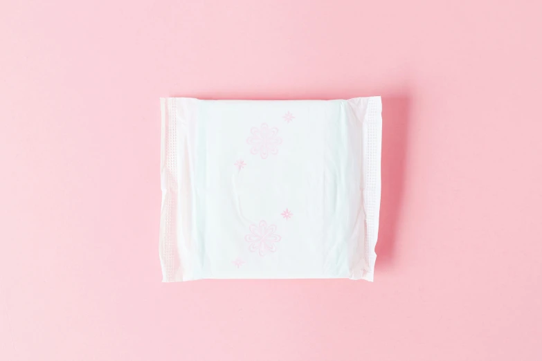 a white towel sitting on top of a pink surface, during the day, contracept, square, no text