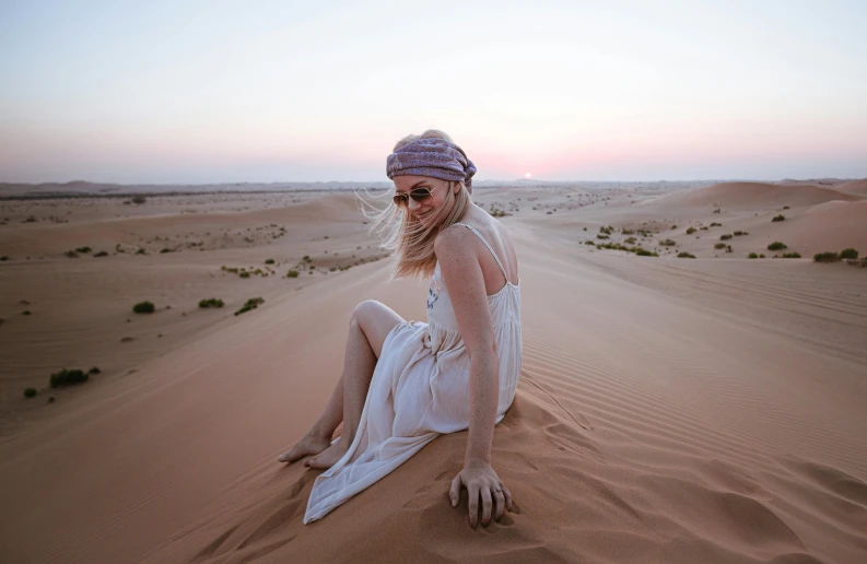 a woman sitting on top of a sand dune, by Alice Mason, pexels contest winner, arabian beauty, instagram post, soft glow, having a good time