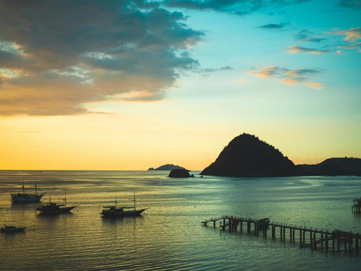 a group of boats floating on top of a body of water, pexels contest winner, sumatraism, summer sunset, hills and ocean, near a jetty, thumbnail