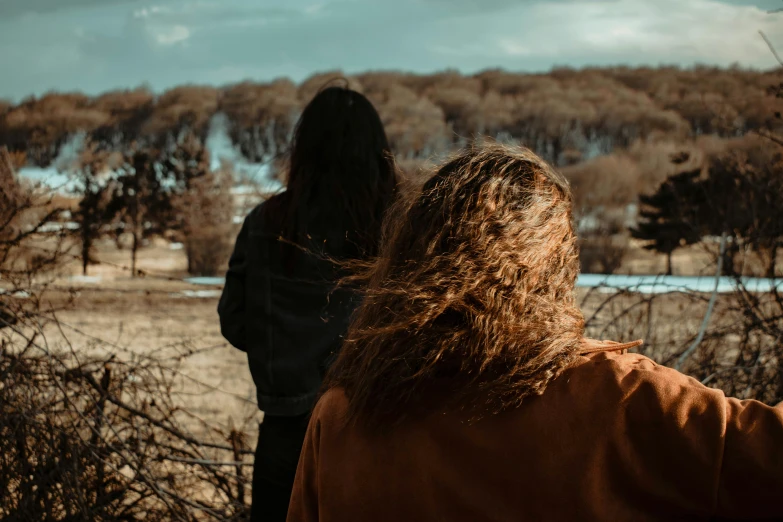 a couple of women standing next to each other, a picture, trending on pexels, happening, brown messy hair, view from a distance, ominous vibe, spring season