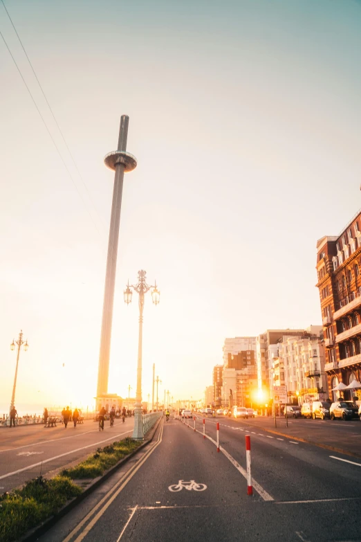 a street filled with lots of traffic next to tall buildings, by Niko Henrichon, unsplash, a road leading to the lighthouse, sun flare, in a beachfront environment, brussels