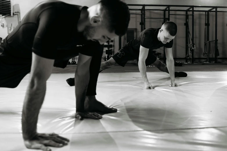 a group of people doing push ups in a gym, a black and white photo, process art, square, mma, slightly minimal, profile image