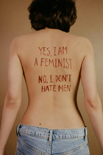 a woman with the words yes i am a feminist, no i don't hate men written on her back, an album cover, 1990s photograph, (digital art), upper body image, bare back