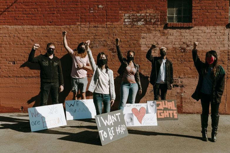 a group of people standing in front of a brick wall, protest, background image