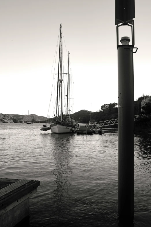 a couple of boats that are in the water, a black and white photo, inspired by Wilhelm Marstrand, low quality photo, ibiza, 8 k -, at dusk!