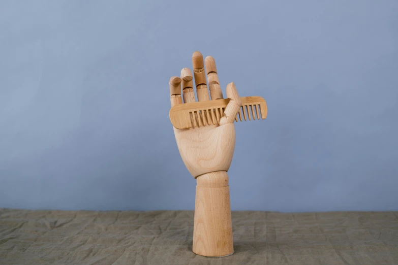 a wooden hand holding a comb on a table, by Pamela Drew, new sculpture, high quality product photo, hero prop, large head, open palm