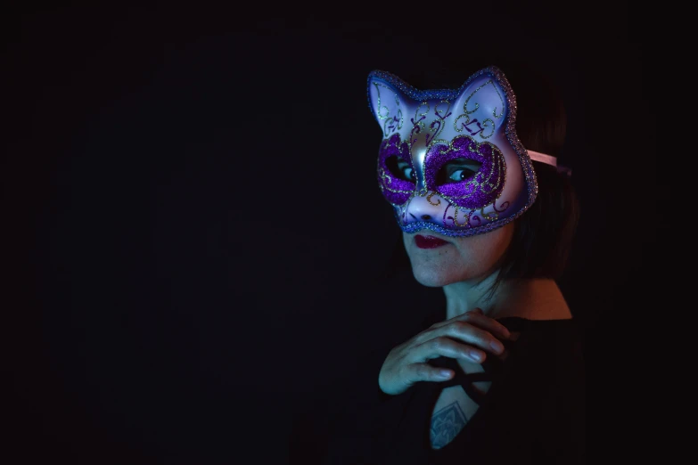 a woman wearing a cat mask in the dark, a portrait, purple and blue, dramatic product shot, artisanal art, the cheshire cat