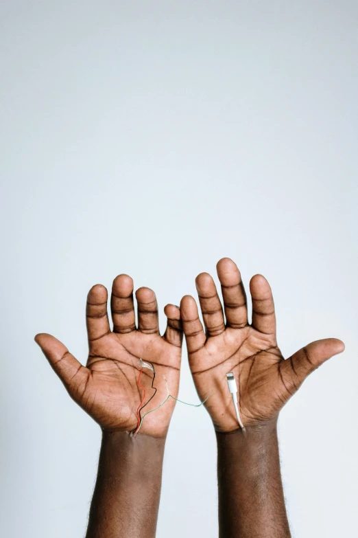 a person holding their hands up in the air, an album cover, by Will Ellis, trending on pexels, hurufiyya, intricate african jewellery, thin wires, plain background, 15081959 21121991 01012000 4k