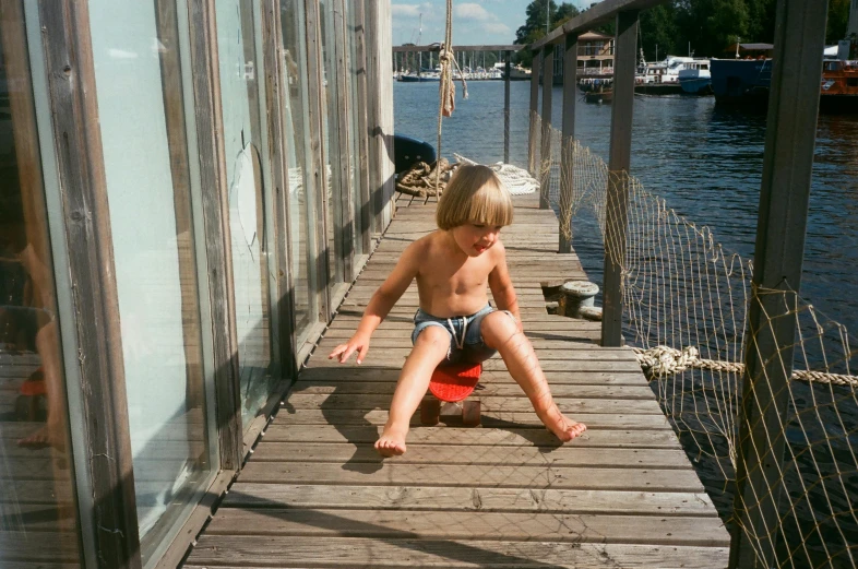a young boy sitting on a fire hydrant on a dock, inspired by Wilhelm Marstrand, unsplash, purism, swedish house, 1970s photo, on a boat, on hasselblaad