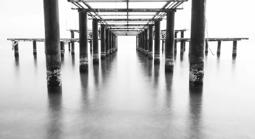 a black and white photo of a pier, unsplash, minimalism, abandoned steelworks, vertical symmetry, medium format, unblur