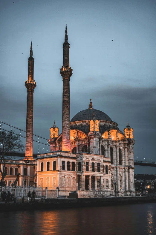 a large building sitting next to a body of water, inspired by Osman Hamdi Bey, pexels contest winner, hurufiyya, black domes and spires, archs and columns, evening lights, 2022 photograph