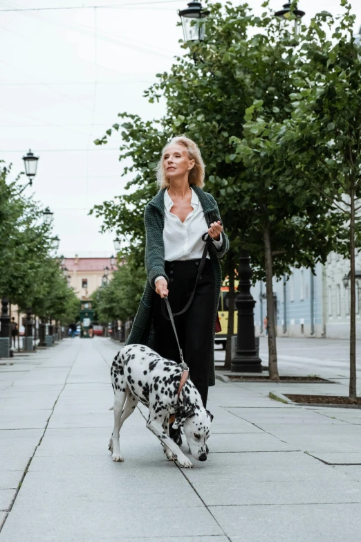 a woman walking a dalmatian dog on a leash, by Grytė Pintukaitė, unsplash, renaissance, square, smart casual, blonde women, style of vogelsang