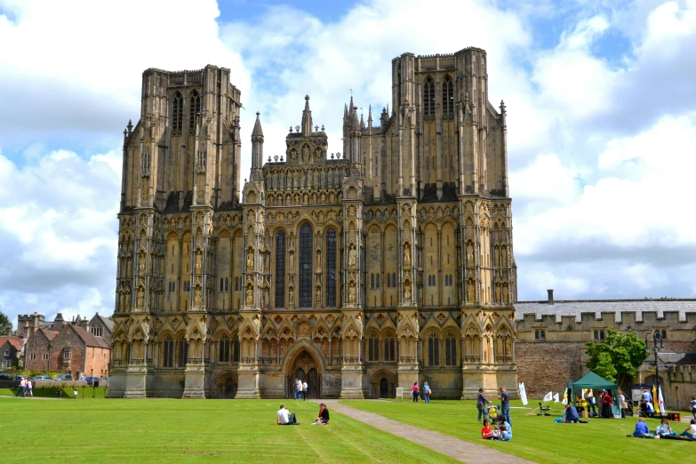 a large cathedral sitting on top of a lush green field, by Rachel Reckitt, pexels contest winner, english heritage, square, van, people walking around