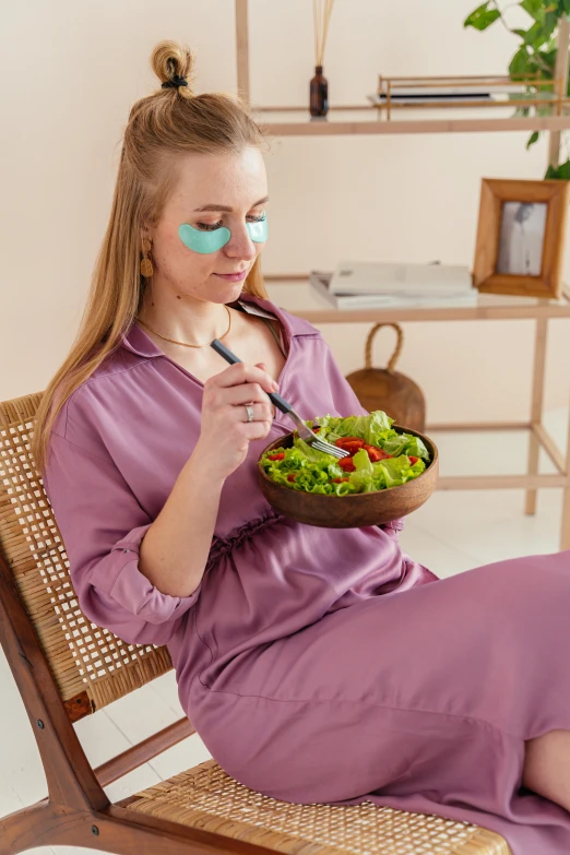 a woman sitting in a chair eating a salad, by Julia Pishtar, trending on instagram, black eye mask, bags under eyes, wearing nanotech honeycomb robe, relaxed colors