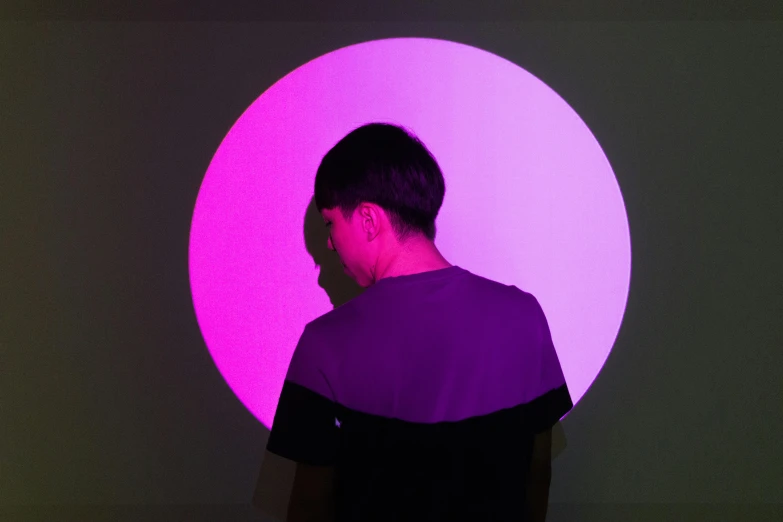 a man standing in front of a purple light, inspired by Russell Dongjun Lu, pexels contest winner, interactive art, circle, set on singaporean aesthetic, looking across the shoulder, half turned around