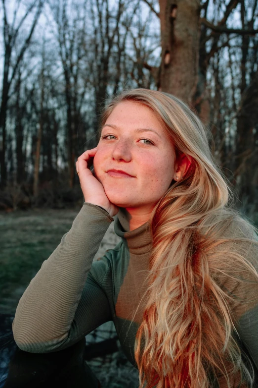 a woman sitting on the ground talking on a cell phone, a picture, by Caroline Mytinger, unsplash, renaissance, long blonde hair and blue eyes, in front of a forest background, headshot profile picture, spring evening