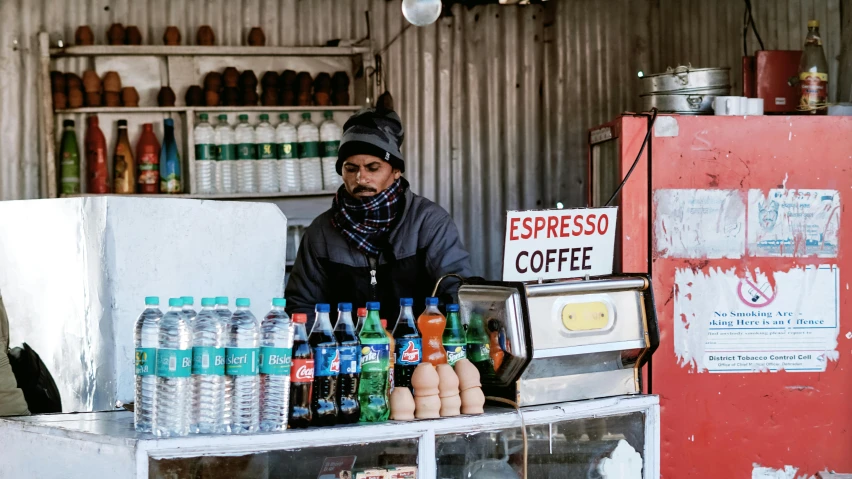 a man that is standing in front of a counter, by Julia Pishtar, pexels, on an indian street, ice coffee, balaclava, chilean