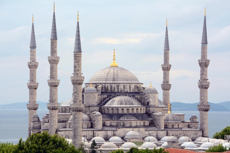 a large building sitting next to a body of water, inspired by Osman Hamdi Bey, pexels contest winner, hurufiyya, with great domes and arches, gray, 🚿🗝📝