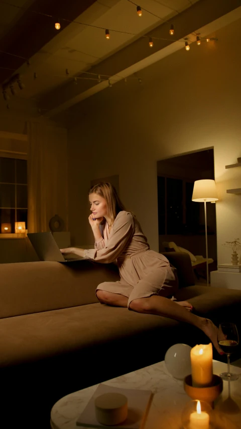 a woman sitting on a couch reading a book, by Eglon van der Neer, pexels, ambient lighting at night, sitting in front of computer, cinematic pastel lighting, beige and dark atmosphere
