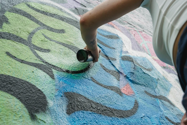a person standing on a skateboard in front of a graffiti covered wall, chalk art, by Grillo Demo, pexels contest winner, high angle close up shot, children painting, thumbnail, public works mural