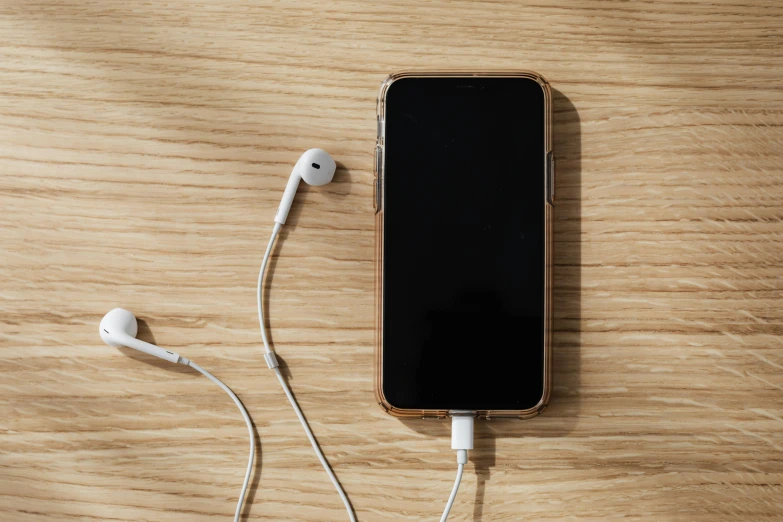 a cell phone sitting on top of a wooden table, trending on pexels, earbuds, gold cables, transparent background, cable plugged in