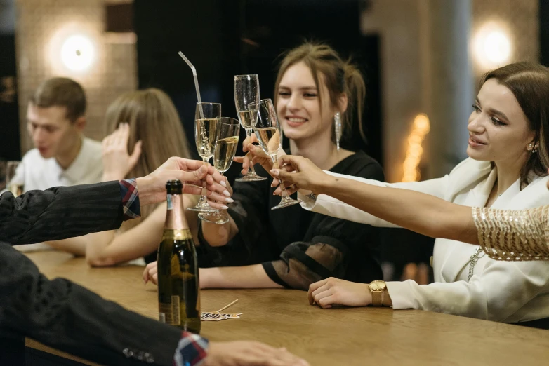 a group of people sitting around a wooden table, champagne, profile image, rectangle, girls