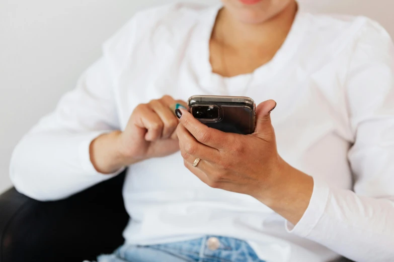 a woman sitting in a chair holding a cell phone, trending on pexels, wearing a white button up shirt, avatar image, bottom angle, handheld