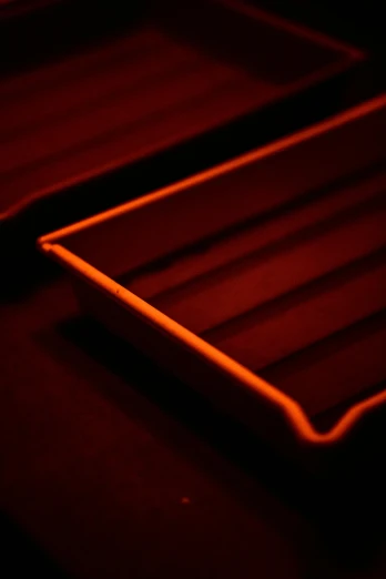 a close up of a tray on a table, by Adam Chmielowski, neon glowing lines, fiery red, photography ultrafine detail, dark orange