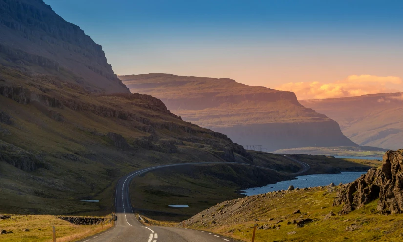 a road going through a valley with mountains in the background, by Hallsteinn Sigurðsson, pexels contest winner, hurufiyya, cliff side at dusk, mountains and lakes, slate, beautiful sunny day