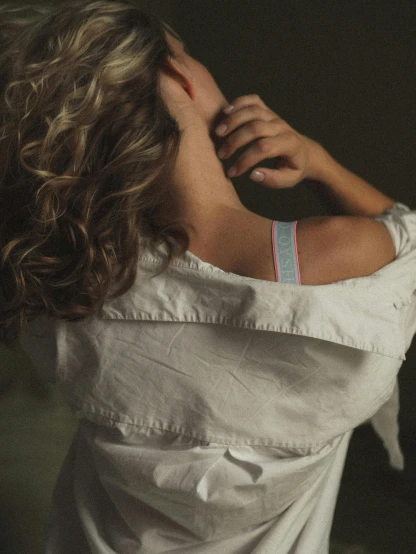 a woman with curly hair wearing a white shirt, inspired by Elsa Bleda, bandage on arms, colour photograph, color image, bra strap