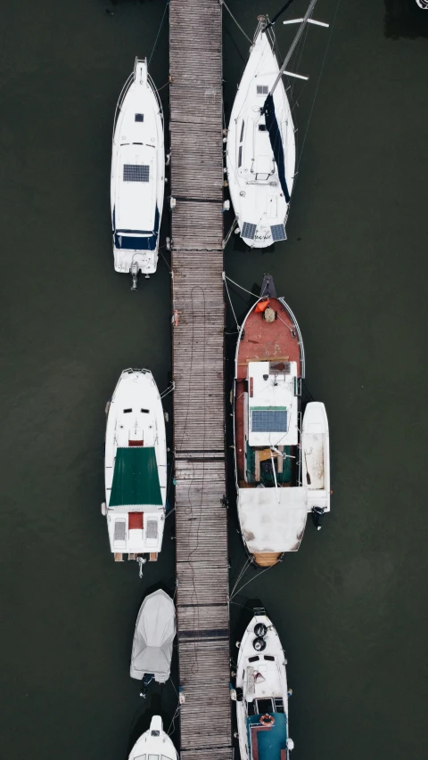 a group of boats parked next to each other on a dock, by Jacob Toorenvliet, pexels contest winner, conceptual art, head straight down, brown and white color scheme, a green, mid air shot