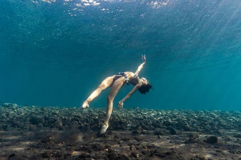 a woman in a bikini swimming in the ocean, an album cover, by Jessie Algie, unsplash contest winner, happening, acrobatic pose, maui, ocean floor, lorde