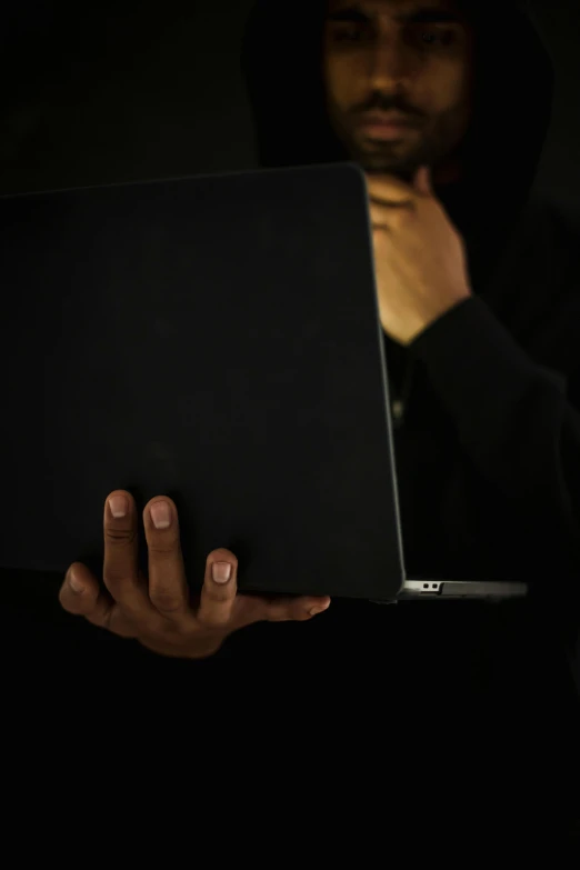 a man in a hoodie holding a laptop, pexels, pitch black skin, 15081959 21121991 01012000 4k, hands hidden, black main color