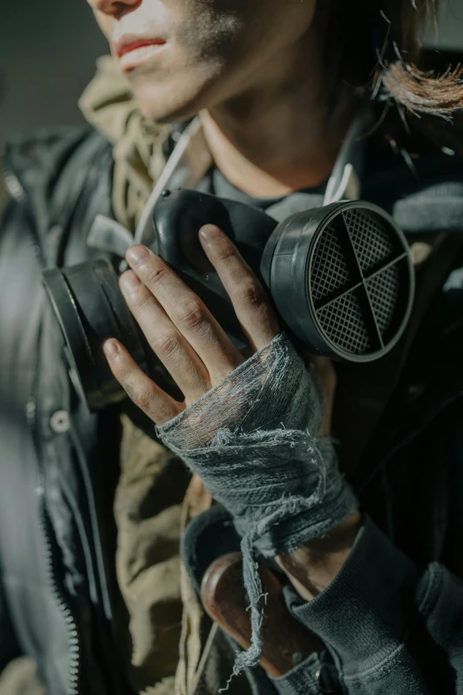 a close up of a person wearing a gas mask, a picture, by Adam Marczyński, trending on pexels, renaissance, wearing torn clothes, holding a dslr camera, film still from 'tomb raider', leather gloves