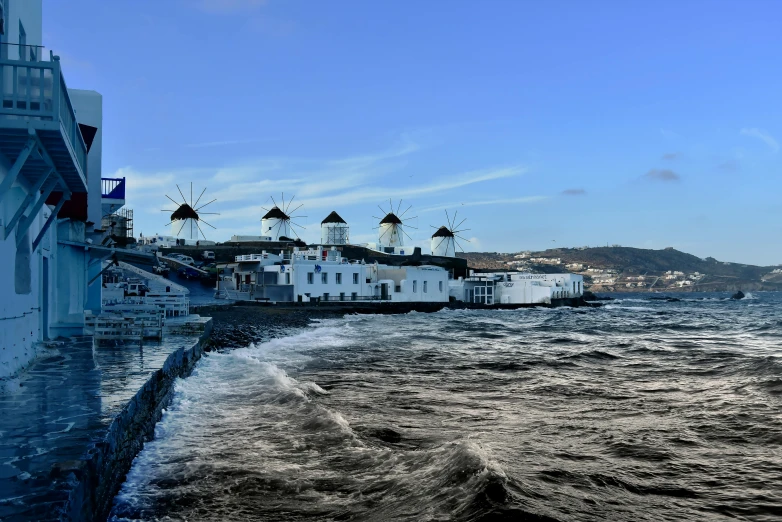 a large body of water next to a white building, pexels contest winner, hurufiyya, windmills, sea spray, greek nose, vallejo