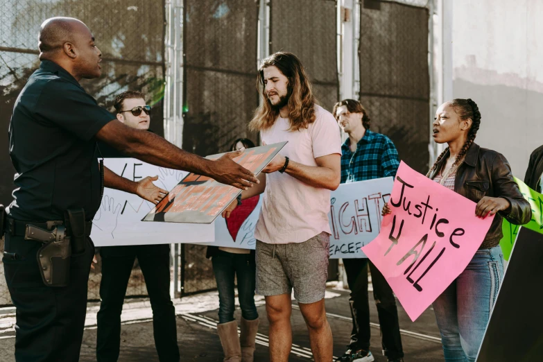 a group of people holding signs in front of a building, by Julia Pishtar, pexels contest winner, reaching out to each other, alexis franklin, carson ellis, light from right