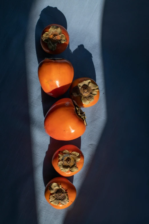 a group of persimmon sitting on top of a table, by Jessie Algie, close-up from above, blue sky, back - lit, an intricate