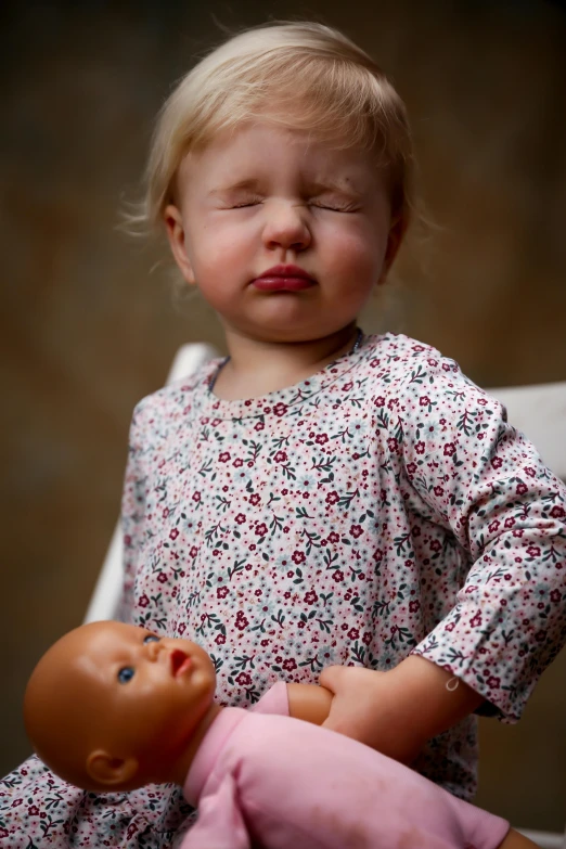 a little girl sitting in a chair with a doll, inspired by Carl Larsson, trending on reddit, crying and puking, exhausted face close up, sleepwear, doll face