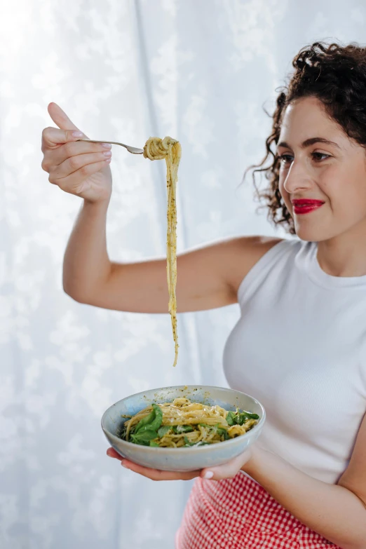 a woman holding a bowl of spaghetti with a fork, inspired by Josefina Tanganelli Plana, curls on top, green, award - winning, mustard