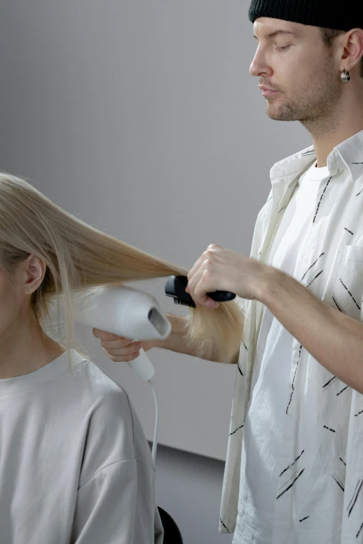 a man is blow drying a woman's hair, inspired by Wilhelm Hammershøi, pexels contest winner, platinum blond, simetrical medium shot, detailed product image, aurora aksnes